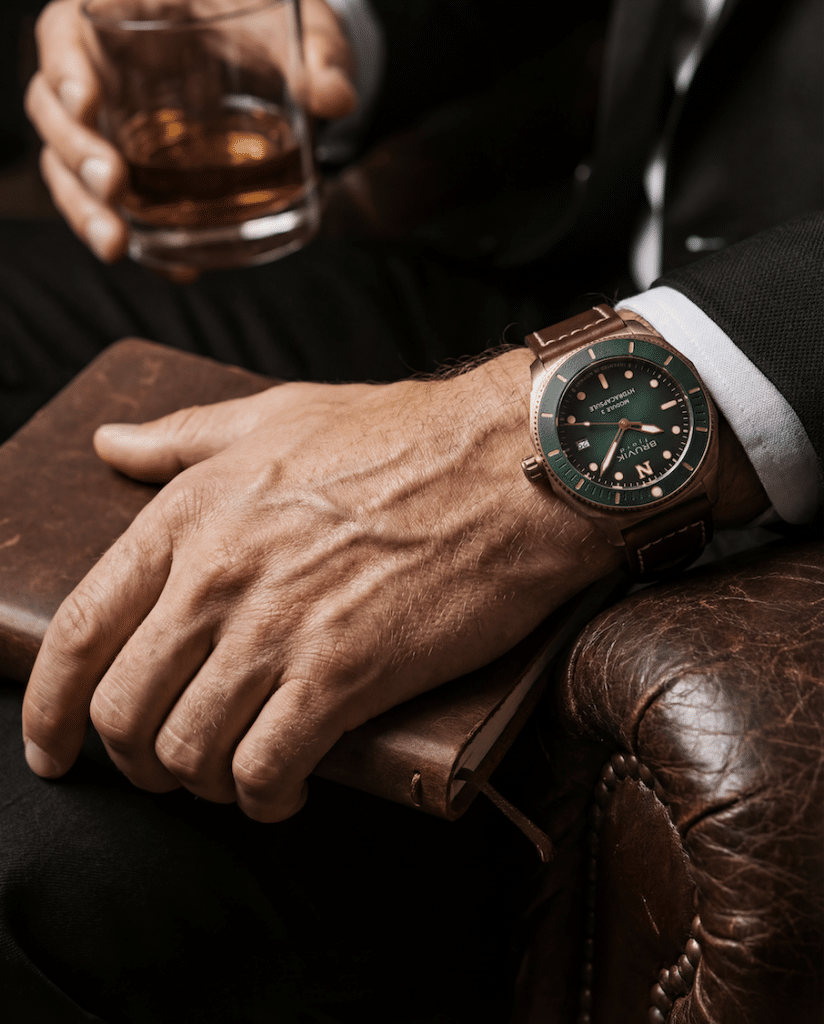 Grønn bruvik klokke på håndledd på brunt armlene